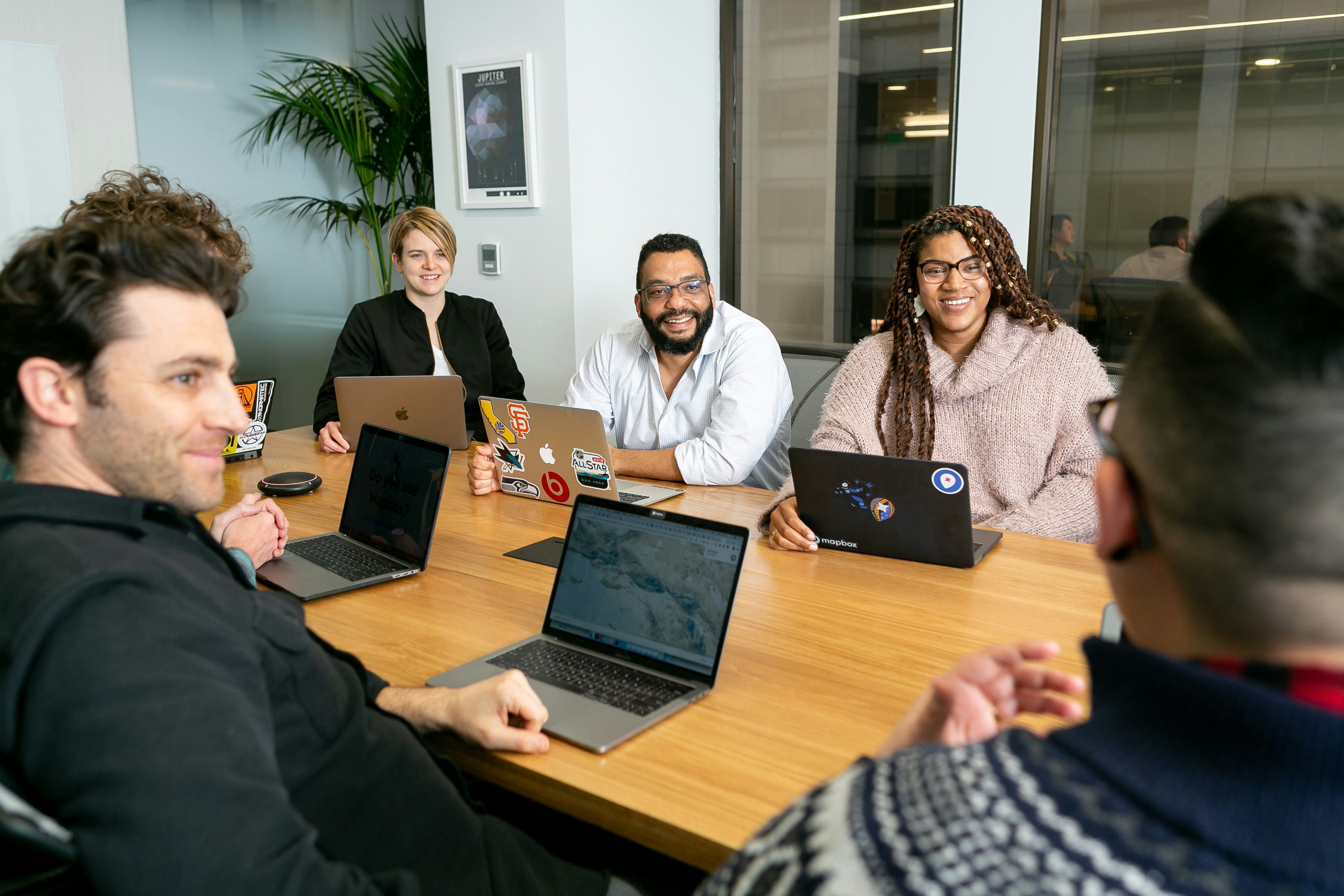 Small business team collaborating around a conference table with laptops